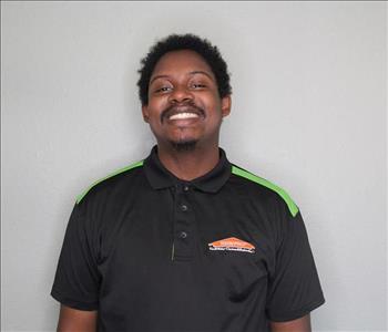 Male employee with brown hair smiling in front of a grey background.