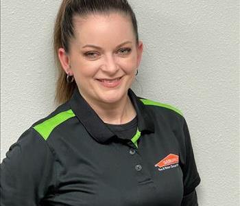 Female employee in black shirt standing in front of a gray background.